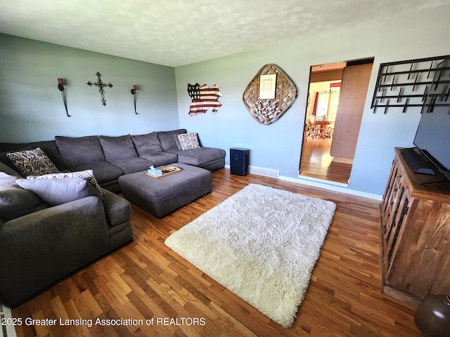 1048 Chris J Dr, Lansing, MI 48917 - living room featuring wood finished floors, baseboards, and a textured ceiling