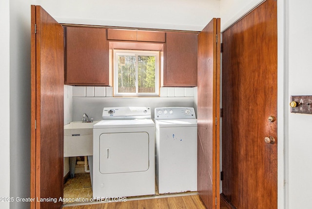 160 Lincoln Hill Dr, Battle Creek, MI 49015 - laundry room featuring washing machine and clothes dryer, cabinet space, and light wood-style floors