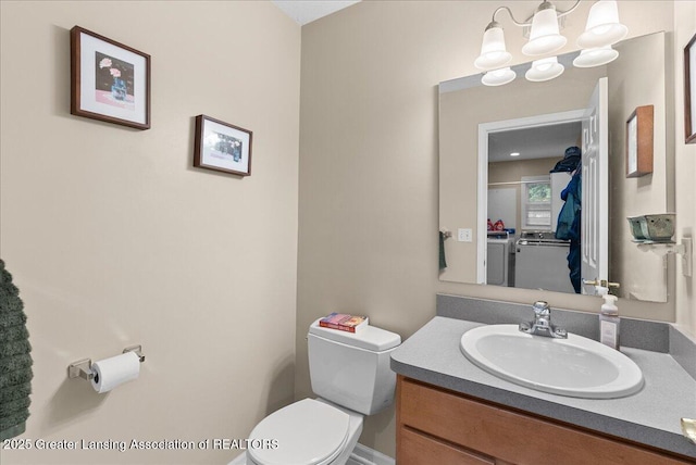 13503 Cottonwood Ct, Dewitt, MI 48820 - bathroom with independent washer and dryer, toilet, vanity, and a chandelier