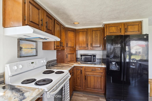 13321 Russell Rd, Lake Odessa, MI 48849 - kitchen featuring black fridge, white electric stove, stainless steel microwave, under cabinet range hood, and brown cabinets