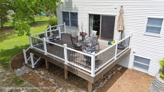 wooden terrace featuring a lawn and outdoor dining space