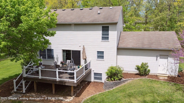 rear view of property with a shingled roof, a deck, and a lawn