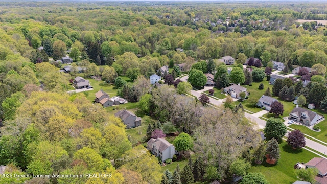 aerial view of property and surrounding area with a heavily wooded area and nearby suburban area