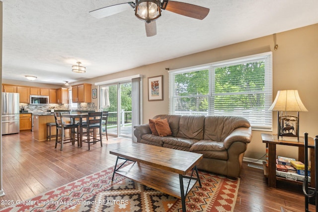 living room with ceiling fan, hardwood / wood-style flooring, and a textured ceiling