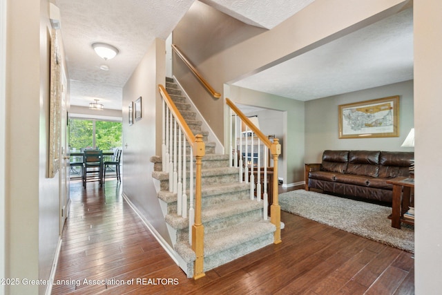 stairs with hardwood / wood-style floors, baseboards, and a textured ceiling