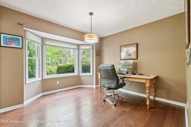 home office with baseboards, wood finished floors, and a textured ceiling