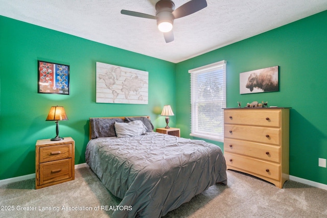 carpeted bedroom featuring a textured ceiling, baseboards, and a ceiling fan