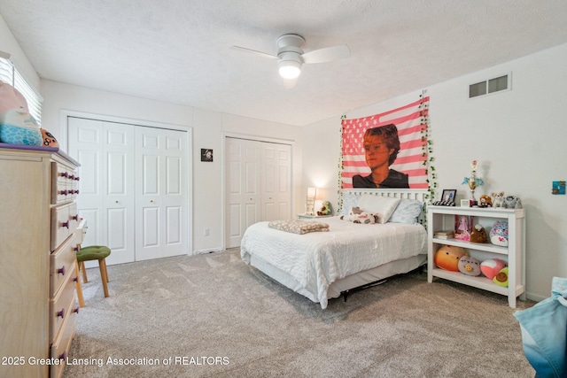 carpeted bedroom featuring multiple closets and a ceiling fan