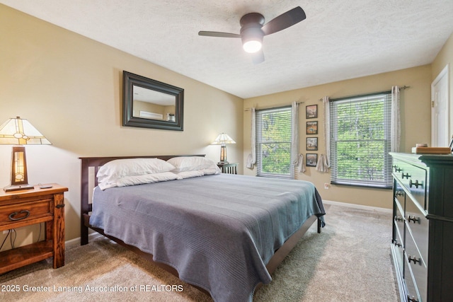 carpeted bedroom featuring baseboards, ceiling fan, and a textured ceiling