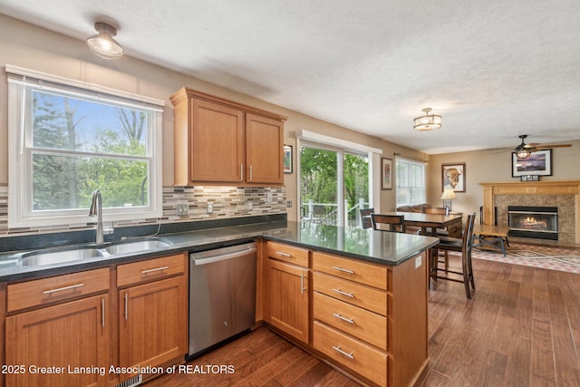 kitchen with dishwasher, a sink, a peninsula, a ceiling fan, and dark wood-type flooring