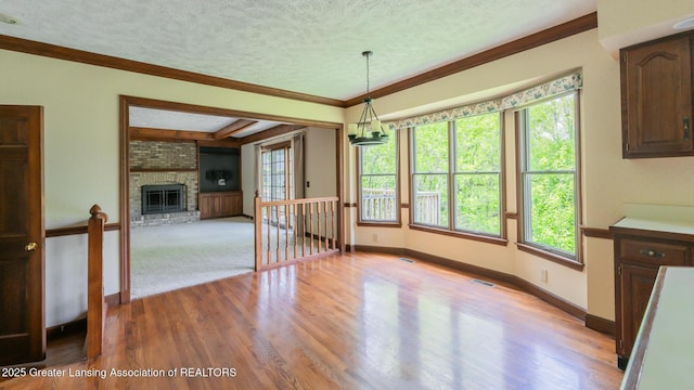 4245 Sandridge Dr, Okemos, MI 48864 - unfurnished dining area featuring a textured ceiling, ornamental molding, light wood finished floors, a fireplace, and baseboards