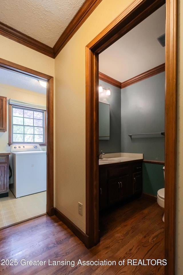 4245 Sandridge Dr, Okemos, MI 48864 - bathroom featuring washer / clothes dryer, wood finished floors, crown molding, vanity, and a textured ceiling
