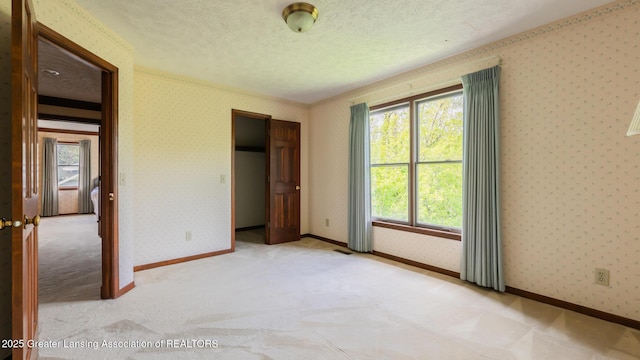 4245 Sandridge Dr, Okemos, MI 48864 - unfurnished bedroom featuring multiple windows, light colored carpet, wallpapered walls, a textured ceiling, and baseboards