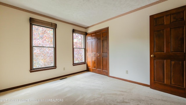 4245 Sandridge Dr, Okemos, MI 48864 - unfurnished bedroom featuring baseboards, a closet, light carpet, a textured ceiling, and crown molding
