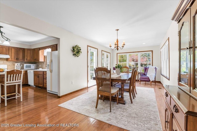 1801 Tahyio Rd, Owosso, MI 48867 - dining area featuring a chandelier, light wood-style floors, and baseboards