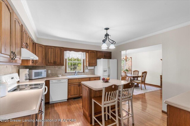 1801 Tahyio Rd, Owosso, MI 48867 - kitchen with white appliances, a sink, under cabinet range hood, ornamental molding, and light wood finished floors