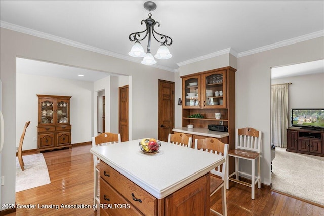 1801 Tahyio Rd, Owosso, MI 48867 - kitchen with light countertops, brown cabinetry, light wood-style flooring, glass insert cabinets, and hanging light fixtures