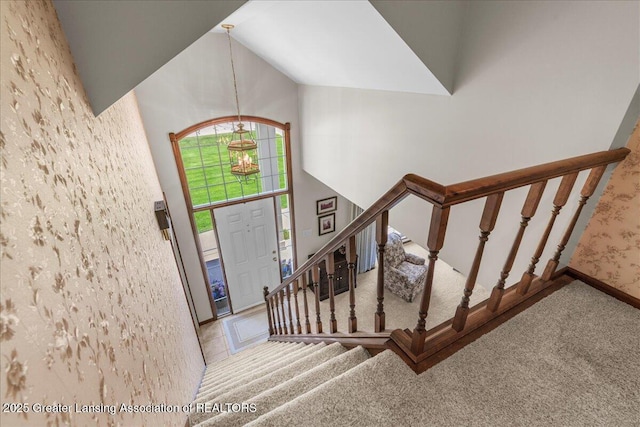 1801 Tahyio Rd, Owosso, MI 48867 - foyer entrance featuring carpet flooring, a chandelier, stairway, high vaulted ceiling, and baseboards
