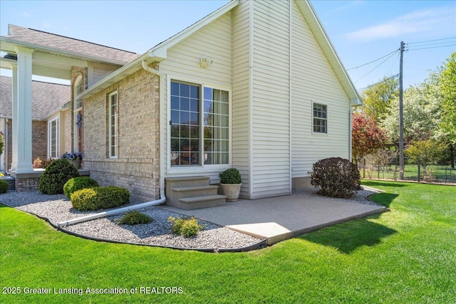 1801 Tahyio Rd, Owosso, MI 48867 - view of home's exterior featuring a patio area, brick siding, a shingled roof, and entry steps