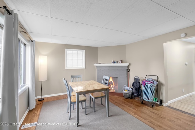 114 Haze St, Lansing, MI 48917 - dining area with a paneled ceiling, wood finished floors, a brick fireplace, and baseboards