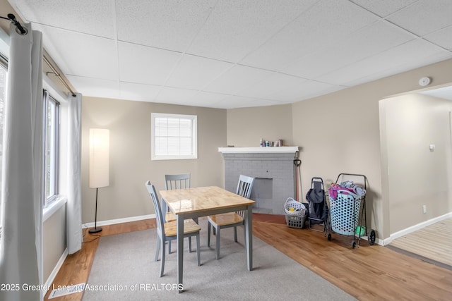 114 Haze St, Lansing, MI 48917 - dining area featuring wood finished floors, a fireplace, a paneled ceiling, and baseboards