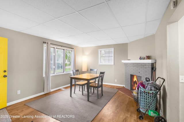 114 Haze St, Lansing, MI 48917 - dining area featuring wood finished floors, a brick fireplace, baseboards, and a paneled ceiling