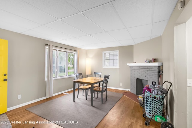 114 Haze St, Lansing, MI 48917 - dining room featuring wood finished floors, a drop ceiling, baseboards, and a fireplace