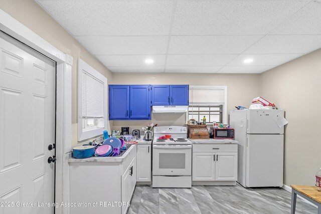 114 Haze St, Lansing, MI 48917 - kitchen with white appliances, under cabinet range hood, light countertops, a drop ceiling, and light marble finish flooring