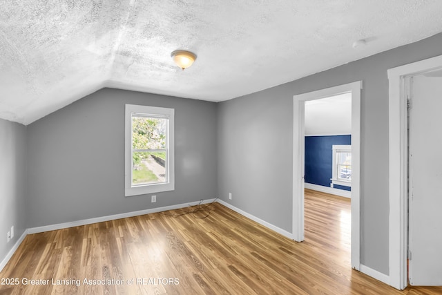 922 Dakin St, Lansing, MI 48912 - bonus room with a textured ceiling, wood finished floors, vaulted ceiling, and baseboards
