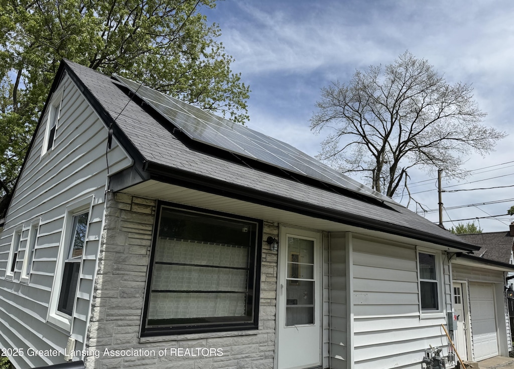 1840 W Maple St, Lansing, MI 48915 - view of home's exterior featuring solar panels and a shingled roof