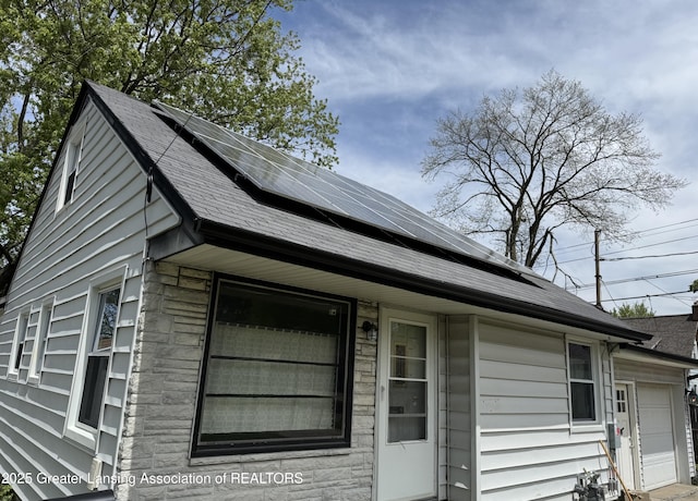 1840 W Maple St, Lansing, MI 48915 - view of home's exterior featuring solar panels and a shingled roof