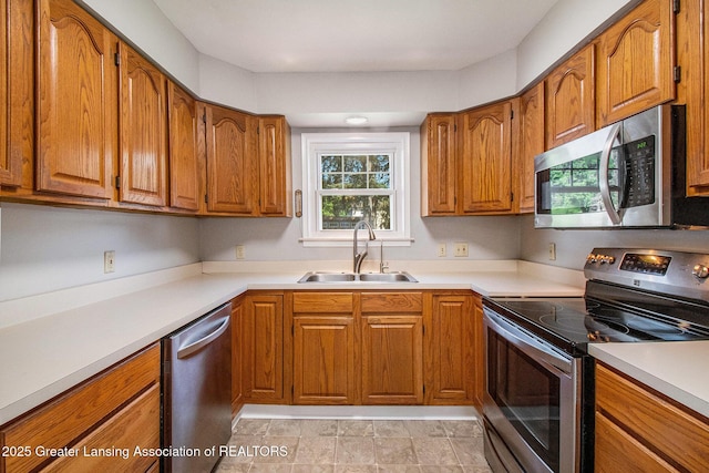 2119 Grant St, Lansing, MI 48910 - kitchen with stainless steel appliances, a sink, brown cabinets, and light countertops