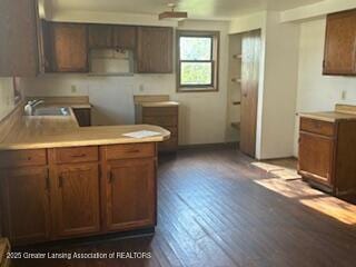 kitchen with a sink, dark wood-style flooring, and light countertops