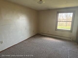 carpeted spare room with baseboard heating and baseboards