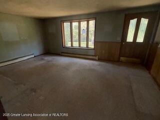 carpeted spare room featuring baseboard heating, a baseboard heating unit, and wainscoting