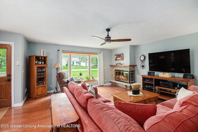 12197 W Greenfield Rd, Lansing, MI 48917 - living area with a glass covered fireplace, light wood-style floors, ceiling fan, and baseboards