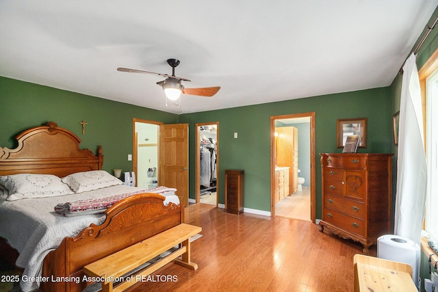 12197 W Greenfield Rd, Lansing, MI 48917 - bedroom with a spacious closet, light wood-style flooring, a closet, ensuite bathroom, and a ceiling fan