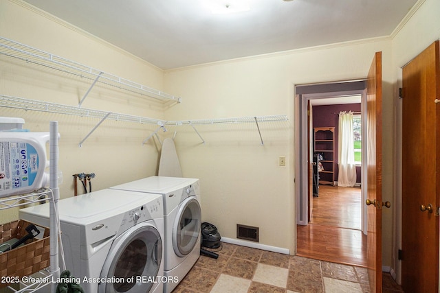 12197 W Greenfield Rd, Lansing, MI 48917 - laundry area with washer and clothes dryer, ornamental molding, baseboards, and stone finish floors