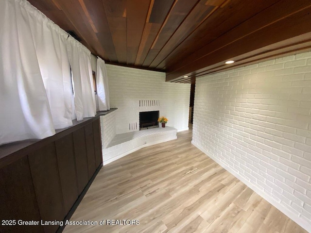 11500 Eden Trl, Eagle, MI 48822 - unfurnished living room with brick wall, a fireplace, and light wood-style floors