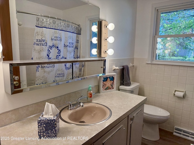 201 W Cavanaugh Rd, Lansing, MI 48910 - full bathroom with tile walls, toilet, wainscoting, vanity, and a shower with shower curtain