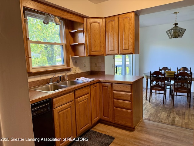 201 W Cavanaugh Rd, Lansing, MI 48910 - kitchen with dishwasher, a sink, light wood-style flooring, brown cabinetry, and decorative backsplash