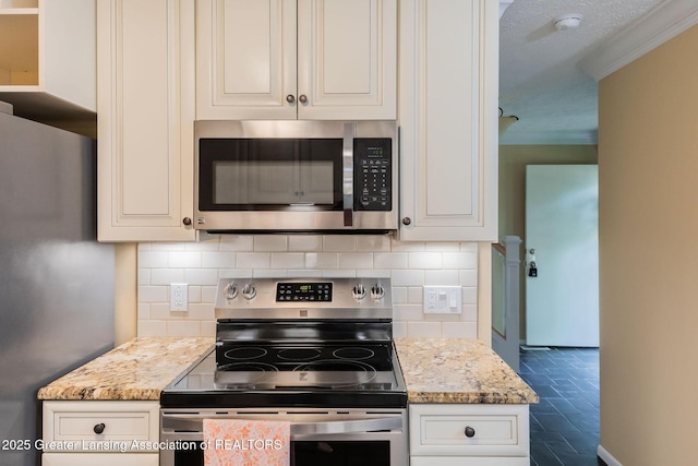 1455 Lakeside Dr, East Lansing, MI 48823 - kitchen featuring stainless steel appliances, tasteful backsplash, ornamental molding, light stone counters, and white cabinetry