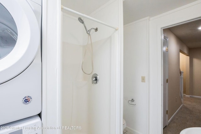 1455 Lakeside Dr, East Lansing, MI 48823 - bathroom with toilet, baseboards, a shower, and stacked washing machine and dryer
