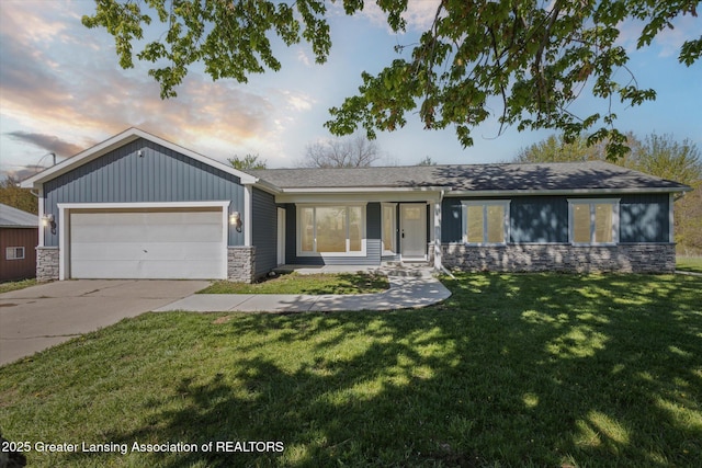 15426 S Lowell Rd, Lansing, MI 48906 - ranch-style home featuring stone siding, an attached garage, concrete driveway, a front yard, and roof with shingles