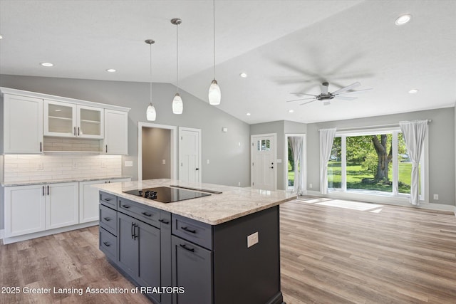 15426 S Lowell Rd, Lansing, MI 48906 - kitchen with light wood-style floors, black electric stovetop, white cabinetry, lofted ceiling, and a ceiling fan