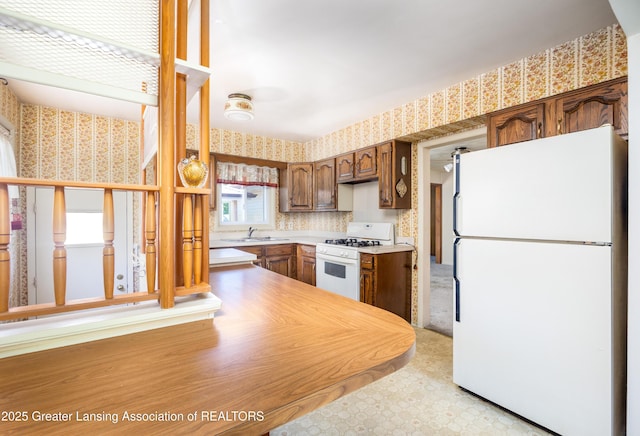 3316 Pickwick Pl, Lansing, MI 48917 - kitchen with white appliances, wallpapered walls, a sink, light countertops, and light floors