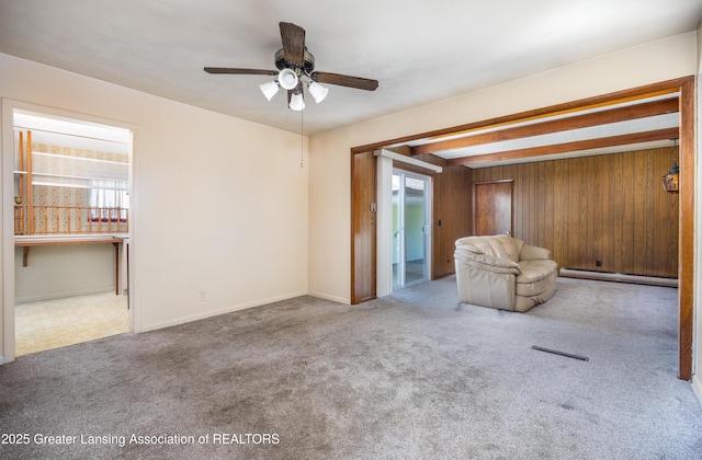 3316 Pickwick Pl, Lansing, MI 48917 - unfurnished living room featuring a baseboard radiator, carpet floors, a ceiling fan, wooden walls, and baseboards