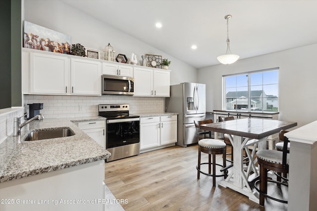 1123 Chesham Ln, Grand Ledge, MI 48837 - kitchen featuring appliances with stainless steel finishes, a sink, backsplash, lofted ceiling, and white cabinetry