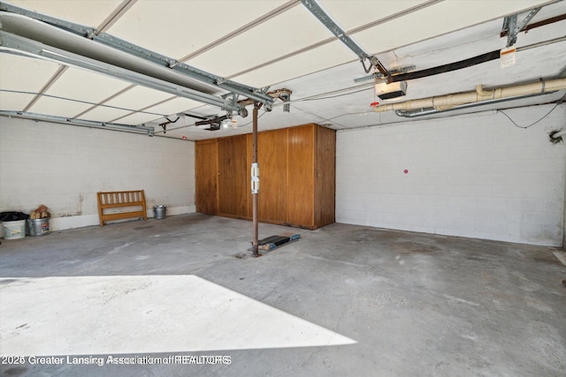 4794 Ardmore Ave, Okemos, MI 48864 - garage featuring a garage door opener and concrete block wall