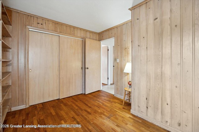 4794 Ardmore Ave, Okemos, MI 48864 - unfurnished bedroom featuring wood walls, wood finished floors, and a closet